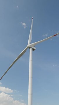 Wind turbine blades spinning against a blue sky generating clean renewable electricity for sustainable development