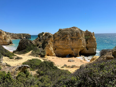 Large weathered rock stack standing on a small beach between cliffs, Albufeira, Algarve, Portugal