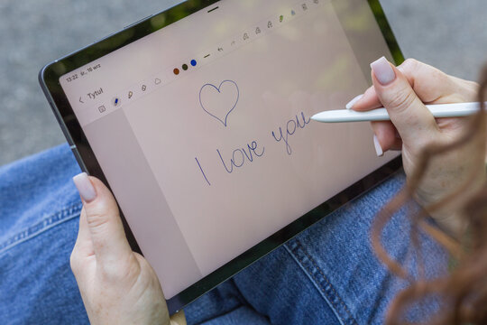 Dłoń pisząca na tablecie &bdquo;I love you&rdquo; z rysunkiem serca, romantyczny gest wyrażający uczucia i bliskość.