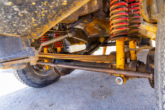 Technical view of a four-wheel-drive front suspension combining leaf springs, auxiliary coil springs and twin shock absorbers on a solid front axle.