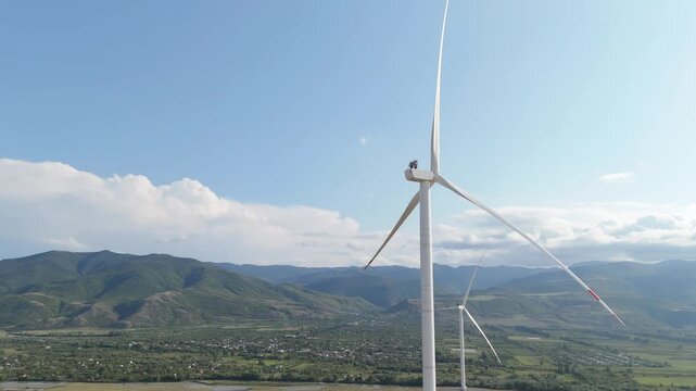 Wind turbines producing renewable energy in a green valley with majestic mountains showcasing sustainable development and ecological power generation for a better future