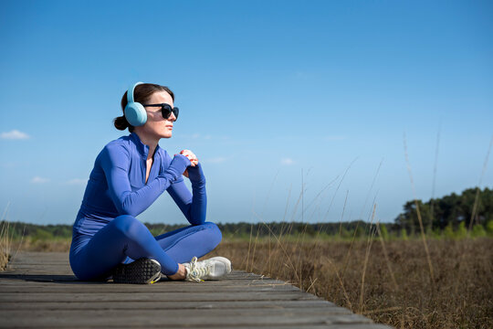 Sporty Woman Relaxing on a Wooden Boardwalk