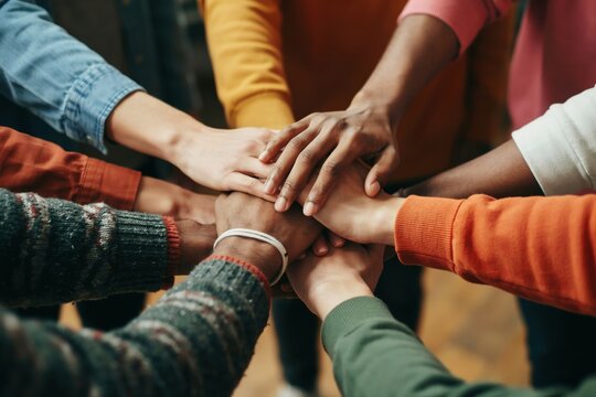 Diverse group of people stacking hands together in a circle