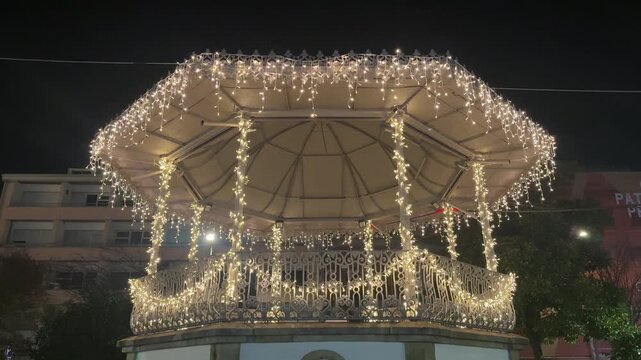 Illuminated gazebo covered with Christmas lights at night, festive holiday scene
