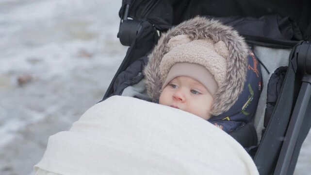 Mother covering baby with blanket in stroller during winter walk