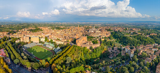 Obraz premium Aerial panoramic view of the Italian famouse city Siena with the landmarks of Basilica di San Domenico, Piazza del Campo tower and Duomo di Siena standing out over the old town center