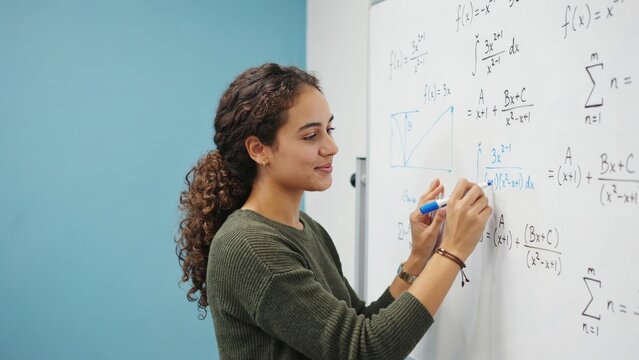 Young woman writing complex calculus equations on a whiteboard