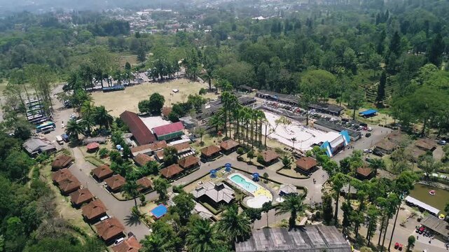 Aerial view of a secluded tropical forest resort with cabins, swimming pool, and recreation areas in the mountains of Southeast Asia.
