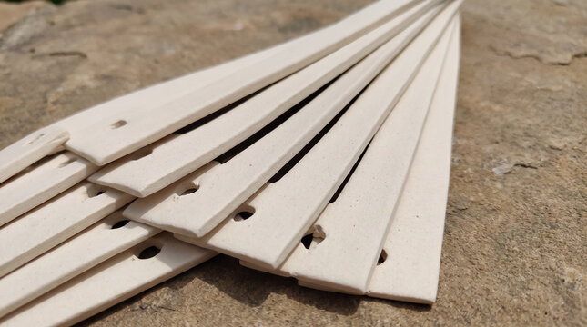 Ceramic kiln spacers and refractory batts with holes on stone surface. Concept of perforations, recessed, ceramic strips, perforated strips, kiln furniture, industrial ceramics, pottery tools.