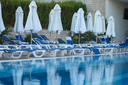Swimming pool area with sunbeds and closed umbrellas at resort