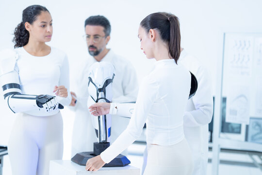 Robotic arm maintenance: a volunteer rests her heavy bionic arm down at her side while two colleagues take over the mounted manipulator for the next service step