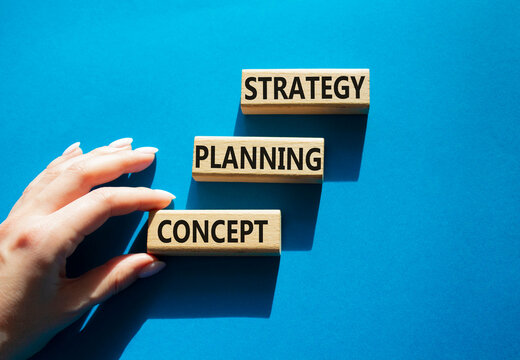 Concept words strategy planning concept on wooden blocks arranged as steps. Businessman hand arranging wooden blocks. Strategic planning and business development concept. Blue background. Copy space.