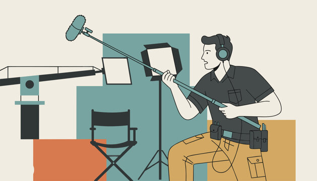 Professional male sound recordist holding a boom microphone on a movie production set with studio lights and a director chair.