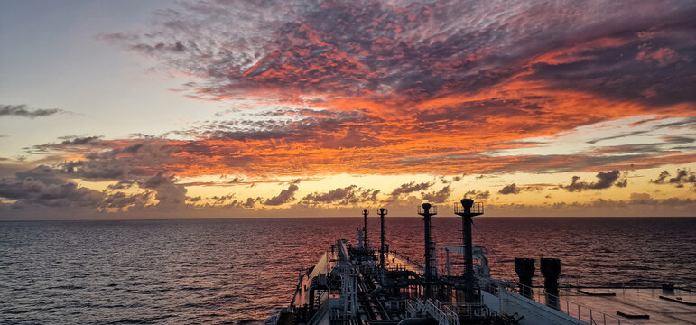 LNG carrier sailing under dramatic orange sunset clouds at sea