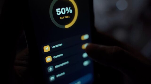 Privacy settings screen on smartphone with app permissions and toggles close-up. Partial protection level indicator in dark room