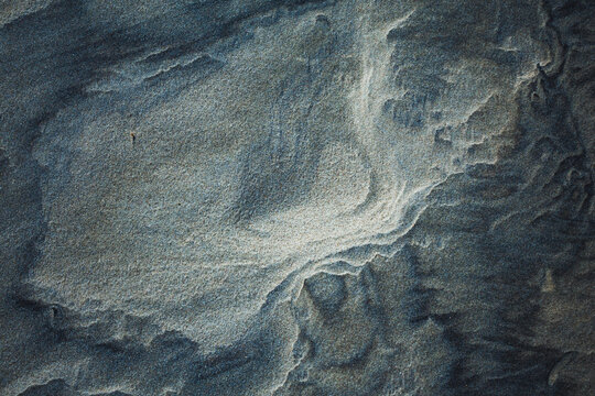 Close-up abstract of perfect wind ripple patterns in white sand dunes forming gentle waves
