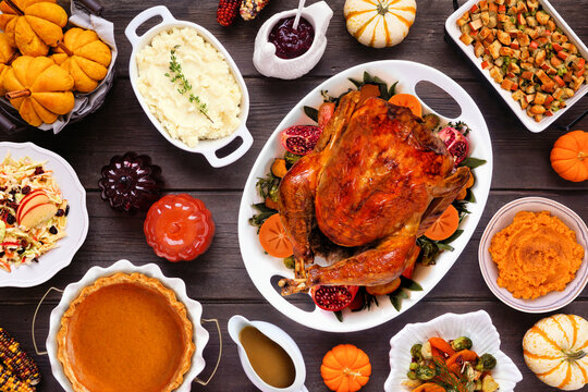 Thanksgiving turkey dinner. Overhead view table scene on a rustic dark wood table background. Turkey, mashed potatoes, stuffing, pumpkin pie and sides.