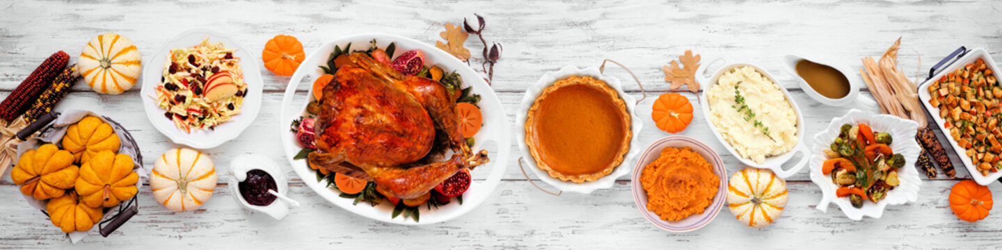 Thanksgiving turkey dinner. Top down view table scene on a rustic white wood table banner background. Turkey, mashed potatoes, stuffing, pumpkin pie and sides.