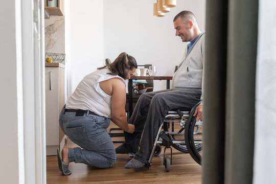 A person with a disability receives dressing assistance from personal assistant in a cozy home setting during the day.