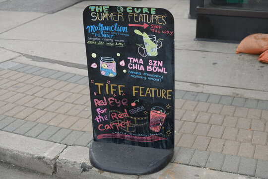 sidewalk black marker board of The Cure by TMA, a health food restaurant, located at 19 Mercer St, Toronto