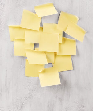 Blank yellow sticky notes clustered on a gray wall for a task list