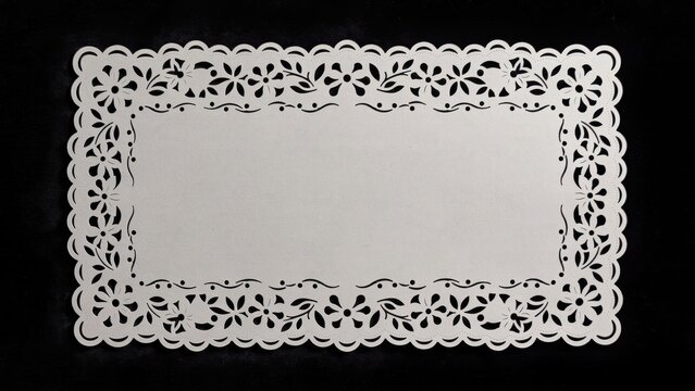 Vintage white lace paper doily, elegant floral laser cut border on black background, decorative rectangular frame for wedding invitations
