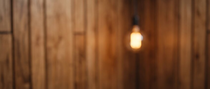 Blurred vintage edison light bulb glowing against a rustic vertical wooden plank wall background