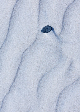 Close-up abstract of perfect wind ripple patterns in white sand dunes forming gentle waves
