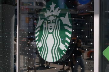 Obraz premium a commercial Starbucks “Siren” logo lightbox inside a window at coffee shop chain location, 10 Dundas St E, The Tenor, Toronto (Sankofa Square)