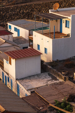 Vista vertical en picado de las casas blancas tradicionales con ventanas azules del poblado costero de Fuencaliente al atardecer en La Palma.
