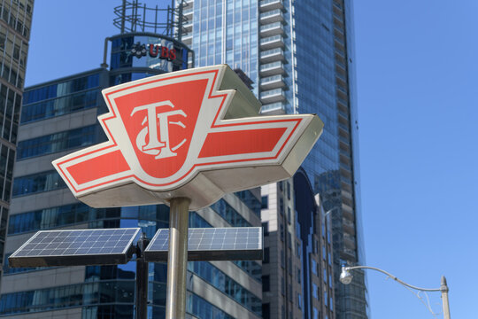subway entrance sign or TTC shield logo sign outside a station on University Av, Toronto (defocused sign of UBS Bank & Wealth Management)