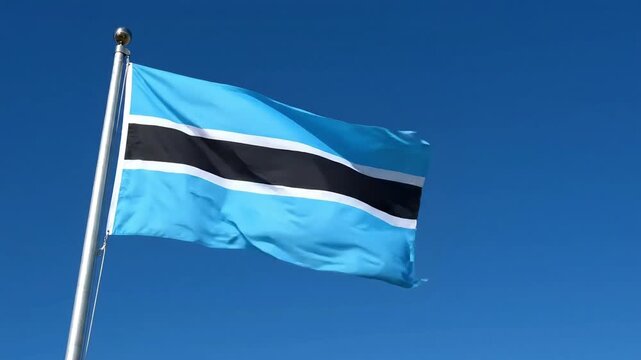 Botswana flag waving on a silver flagpole against a clear blue sky