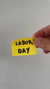 Hand holding labor day sticky note on white background