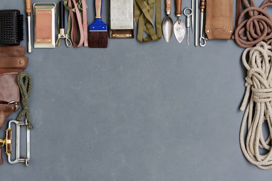 Horse grooming tools and equipment arranged as a border on a dark slate surface with copy space for stable branding