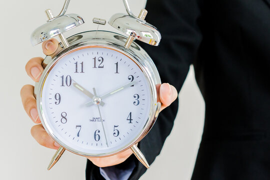 Businessman holding a big vintage alarm clock time management deadline concept
