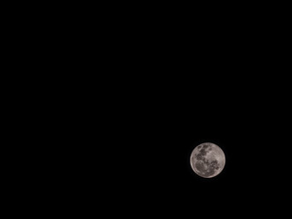 Stunning full moon glowing in a pure black night sky. Detailed lunar craters with a warm pinkish tint © MuhammadRizki