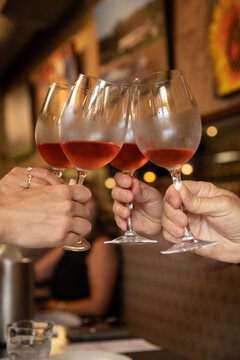 four hands toasting with glass of wine in a bistro