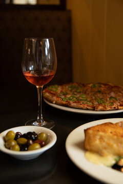 pizza, cheese, olives, and wine on a table at a restaurant