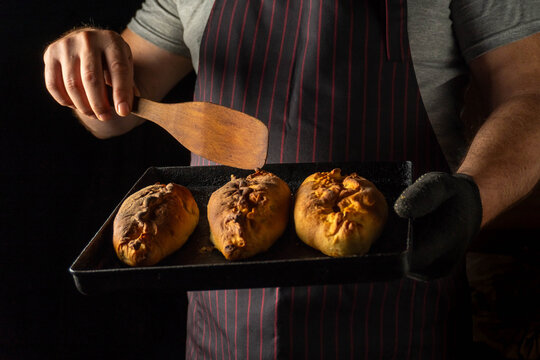 A skilled baker pulls a tray of golden potato bread from the oven, showcasing warm, inviting loaves