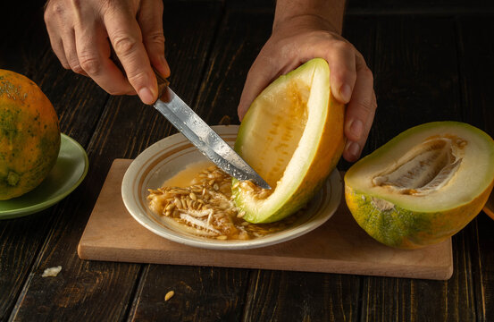 In a cozy kitchen, hands expertly slice through a ripe melon, revealing its golden flesh and seeds. Freshness fills the air as the fruit is prepared for a delightful treat