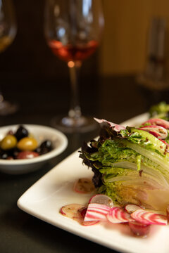 wedge salad with radishes with olives and wine in the background
