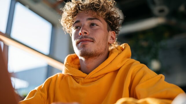 Young Man with Locked Hair, Yellow Hoodie, in Indoor Setting.