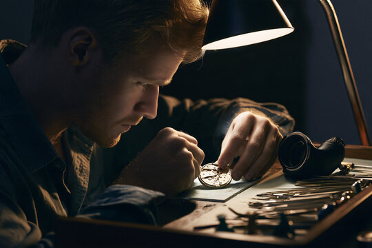 Focused master horologist with a loupe repairing a mechanical watch at a traditional wooden workbench
