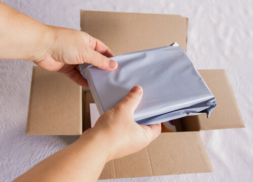 Close-up of a person packing an order, putting a parcel into a delivery cardboard box, online business and shipping concept.