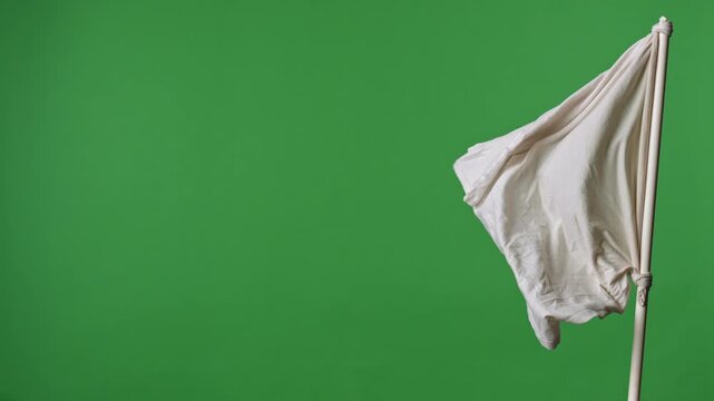 White fabric flag tied to a pole waving against a green background. Concept of surrender, peace, neutrality, truce, symbol, and chroma key template for design and video editing.
