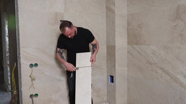 Tiler installing large format tile on bathroom wall using suction cup