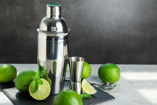Ingredients for mojito, shaker, jigger and spoon on light grey table. Space for text