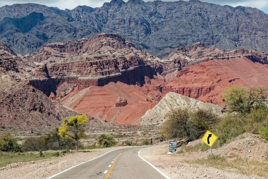 Scenic paved highway Route 68 winding toward Cafayate through the dramatic red rock mountains of Quebrada de las Conchas in Salta, Argentina.