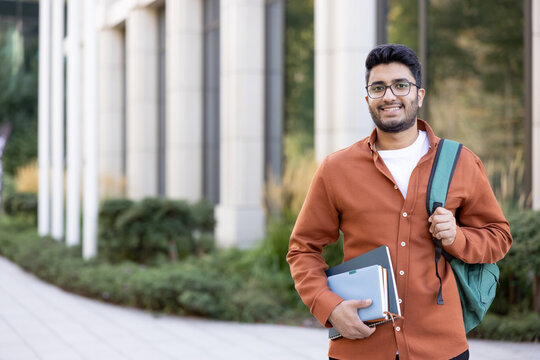 Happy Indian student with backpack and books, university education and academic success.