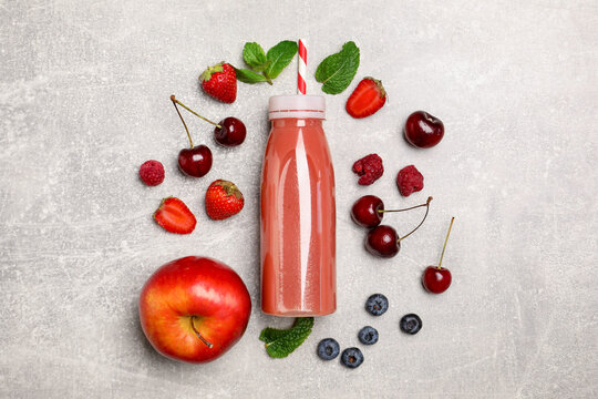 Tasty smoothie in bottle and fresh ingredients on light grey textured background, flat lay